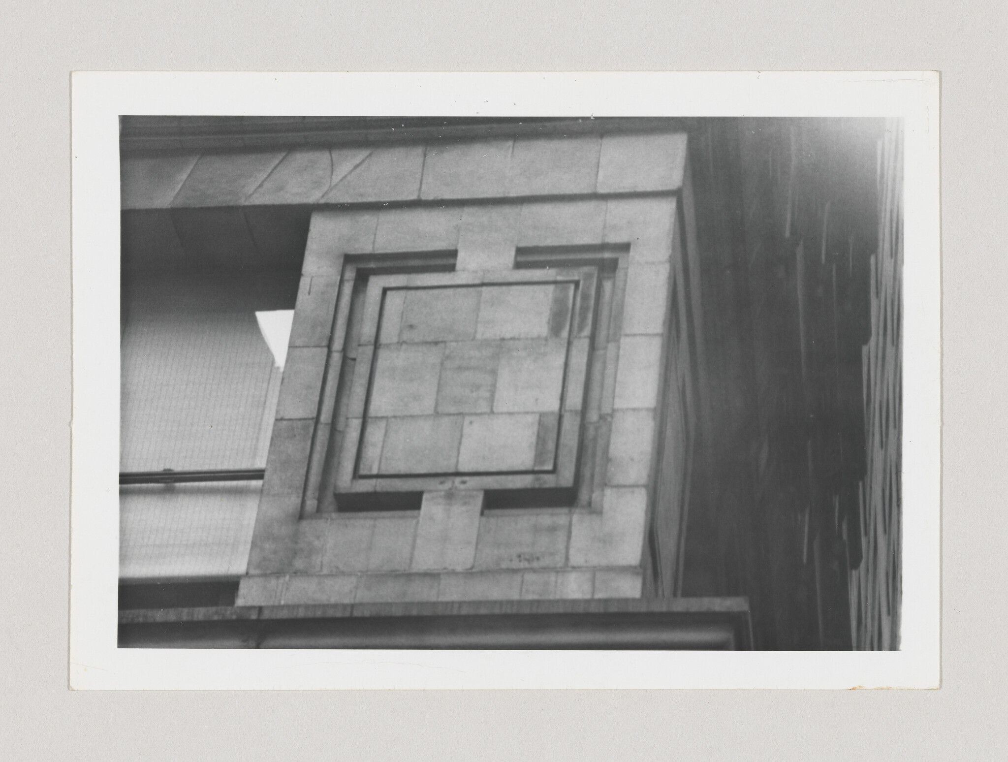 Stone building facade showing a recessed square panel and geometric architectural detailing.
