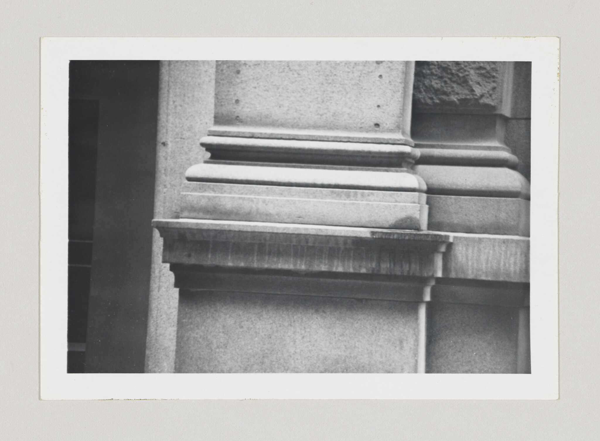 Close-up of a stone column base showing layered moldings and weathered surface.