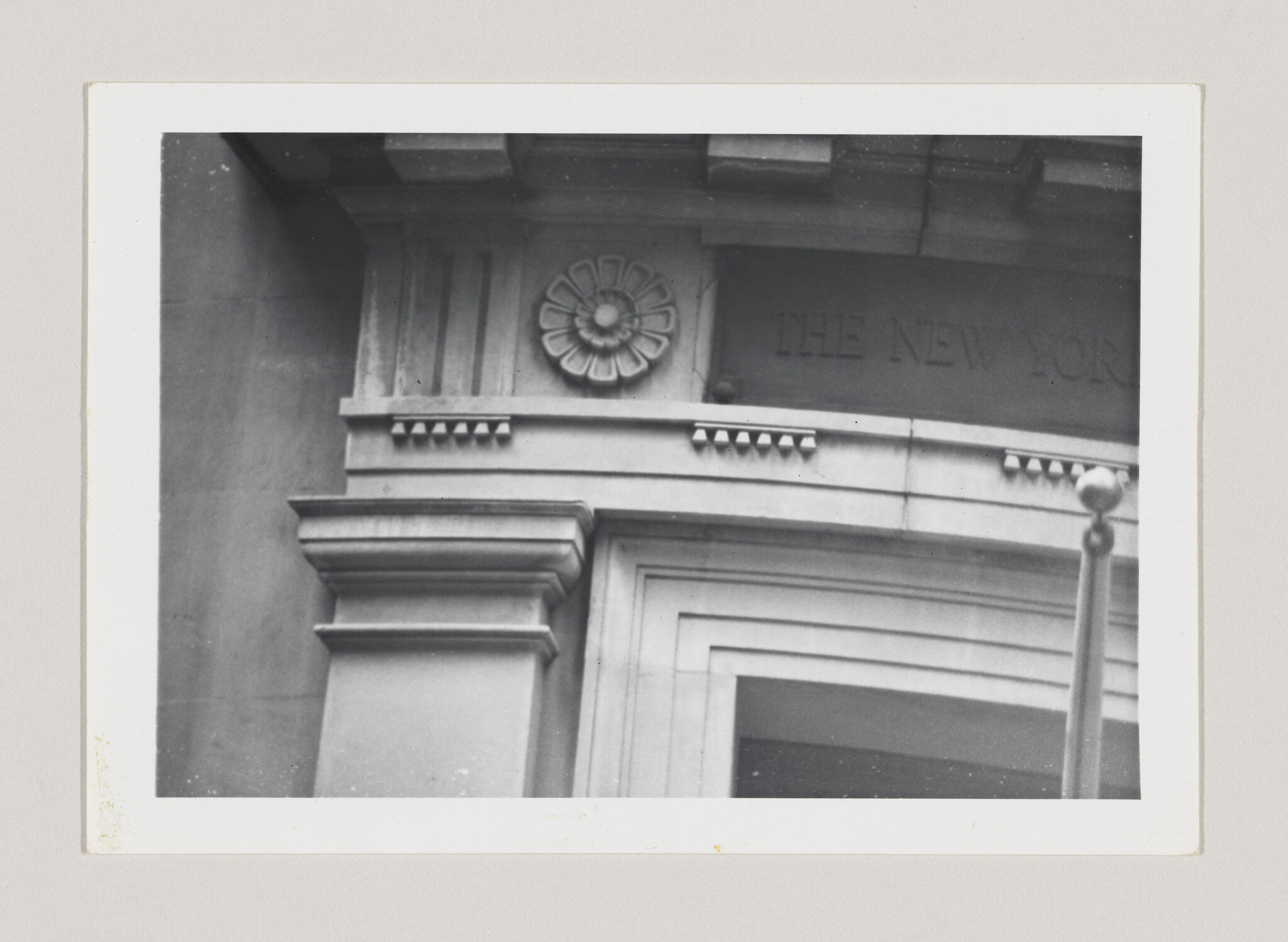Stone building entrance with a decorative rosette above the doorway and part of "The New York" inscription.