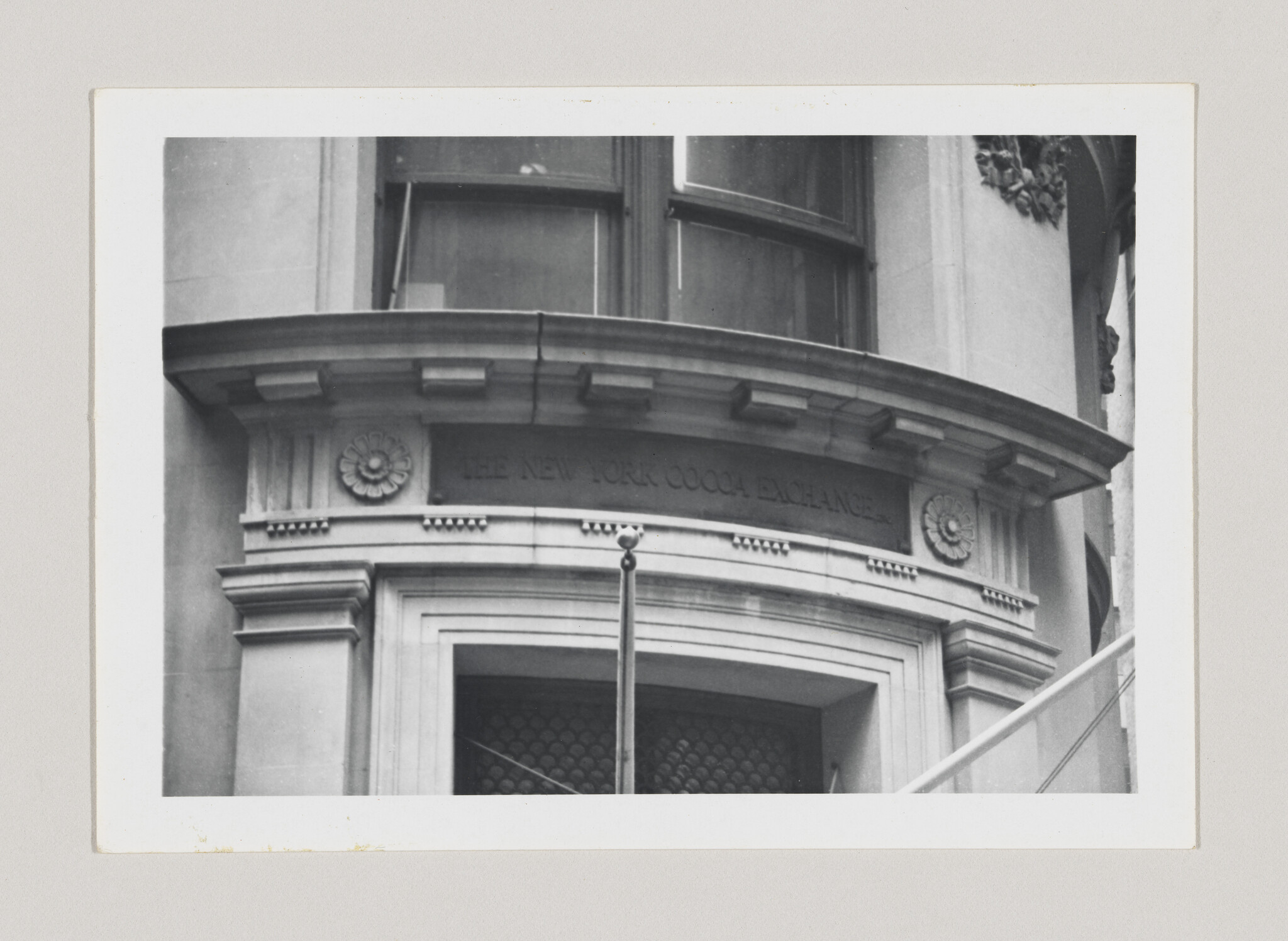 Entrance of the New York Cocoa Exchange building with curved stone lintel and central flagpole.
