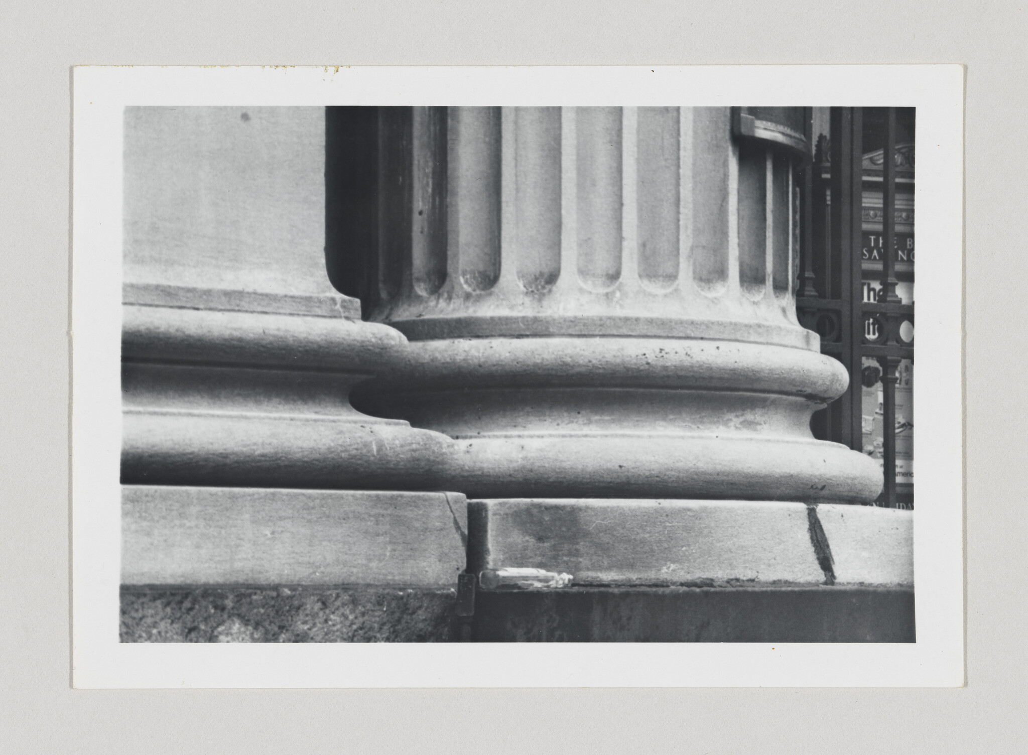Close-up of a stone column base showing fluted shaft, rounded molding, and a visible crack.