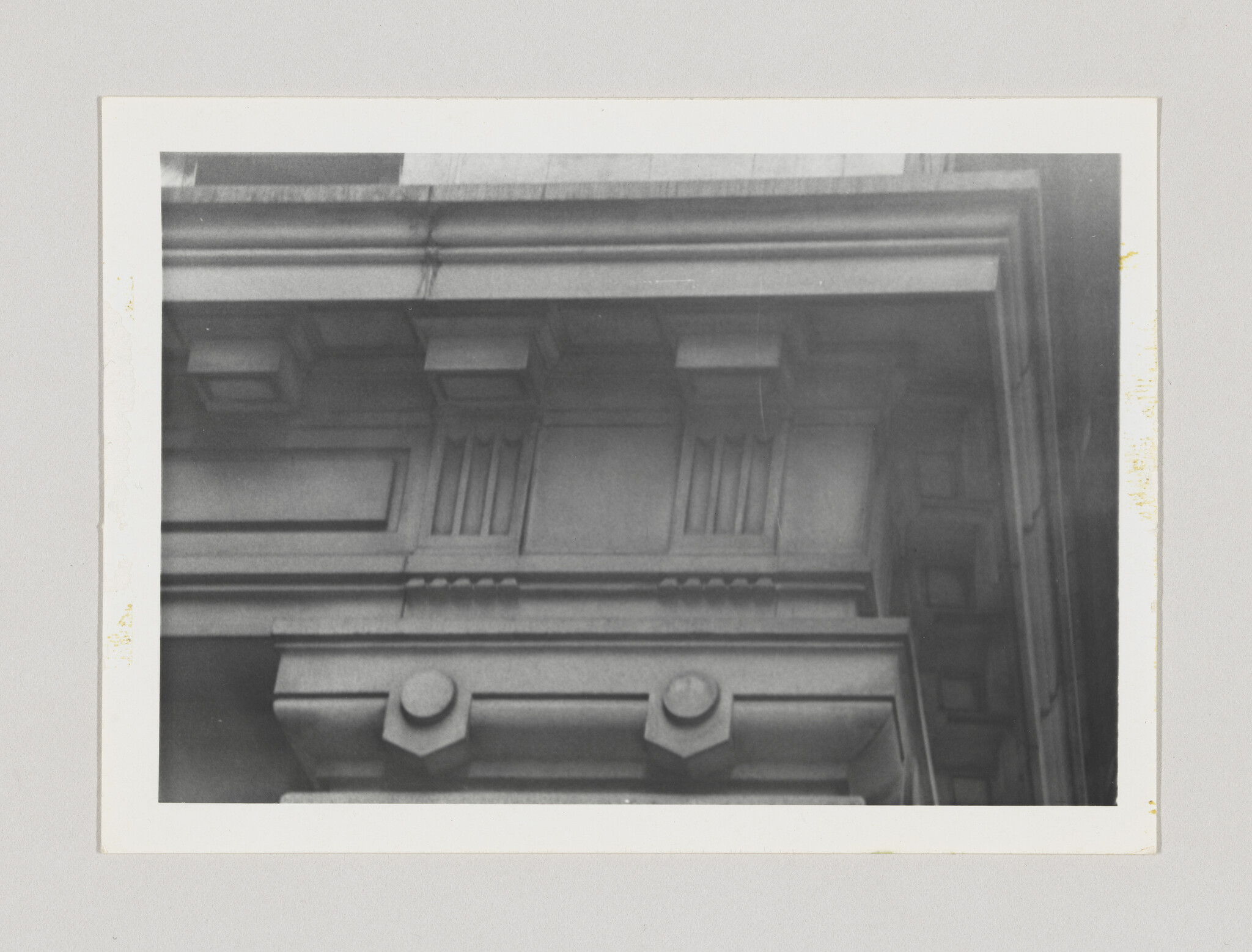 Close-up of a stone cornice with decorative brackets, dentils, and recessed rectangular panels.