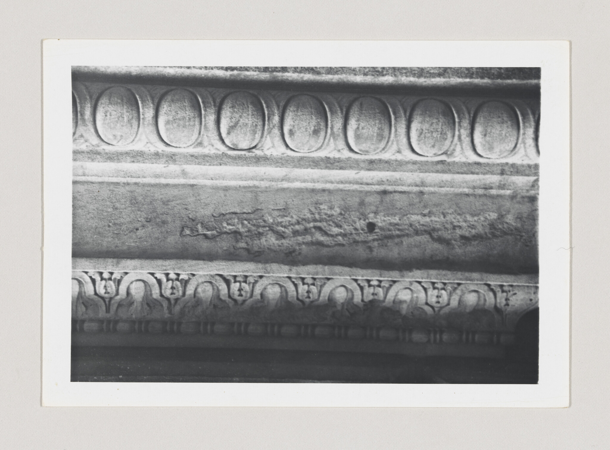 Carved stone frieze showing oval egg-and-dart motifs above a row of floral ornamentation.