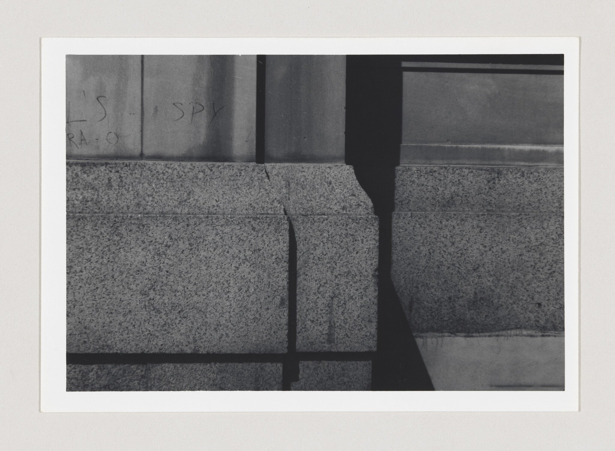 Granite building wall with sharp vertical shadow creating geometric shapes across the surface.