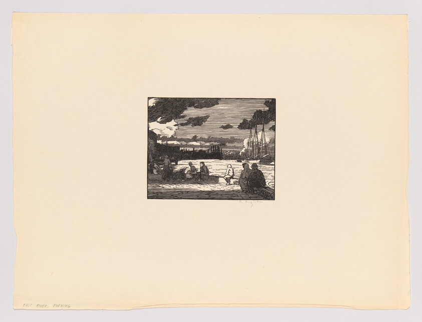 Several people sit and talk along a waterfront with sailboats and cloudy sky in the background.