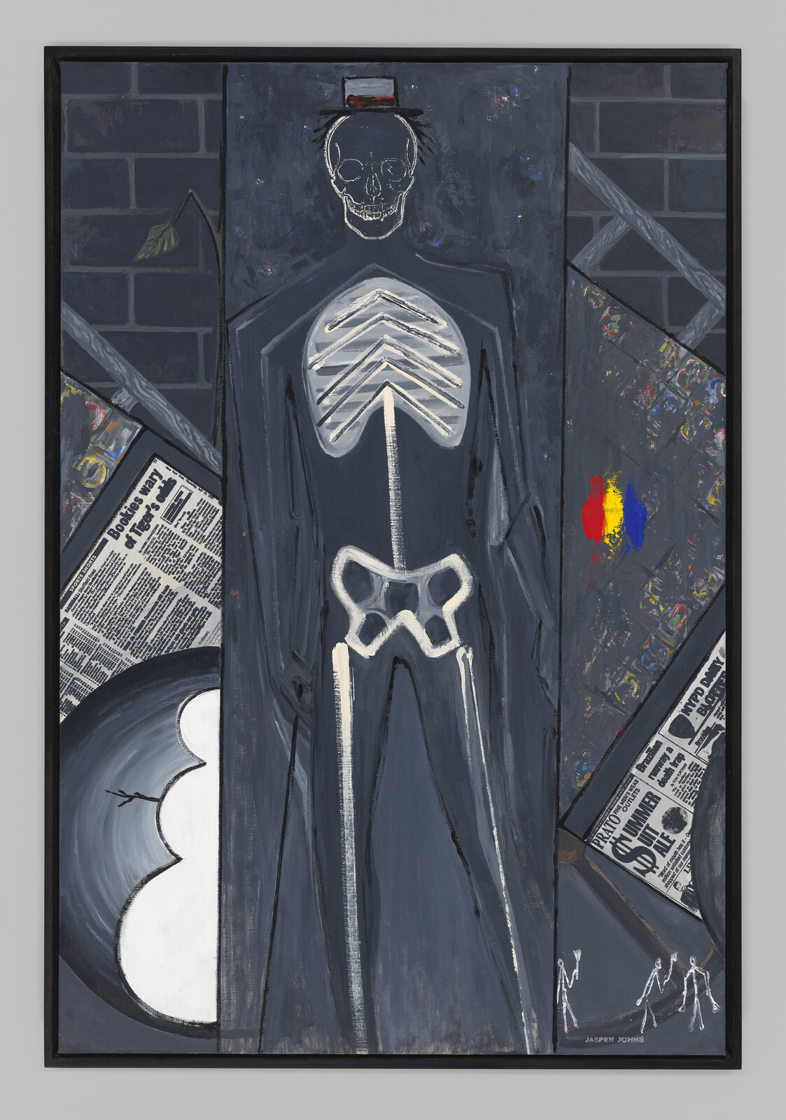 A tall dark painted skeleton figure with white ribs and pelvis stands against a brick backdrop.