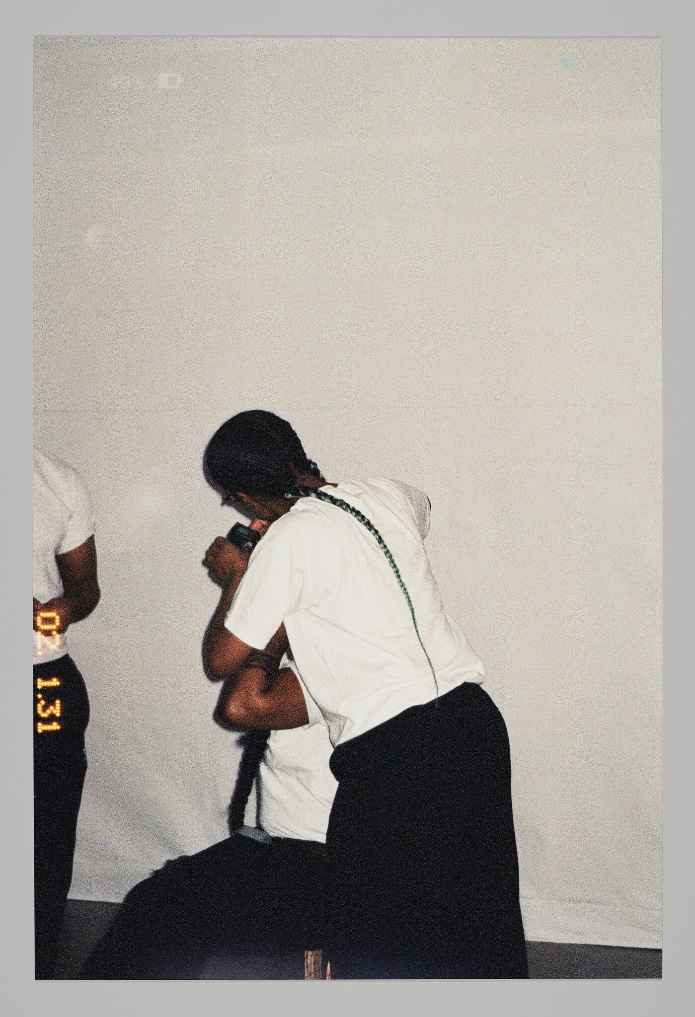 Person with long braid leans over and braids another person's hair while they sit.