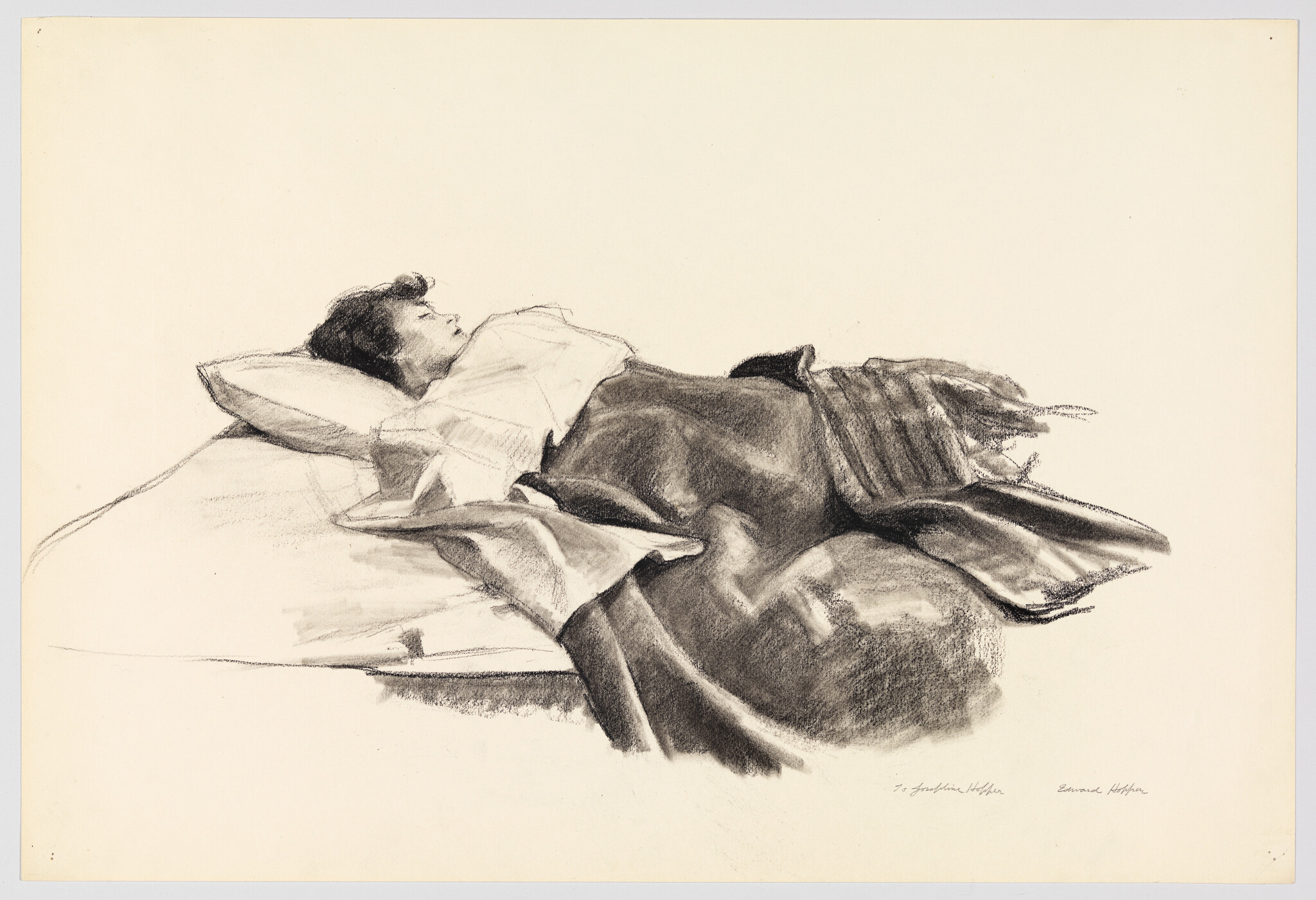 A woman lies asleep on a bed with a blanket pulled up to her chest.