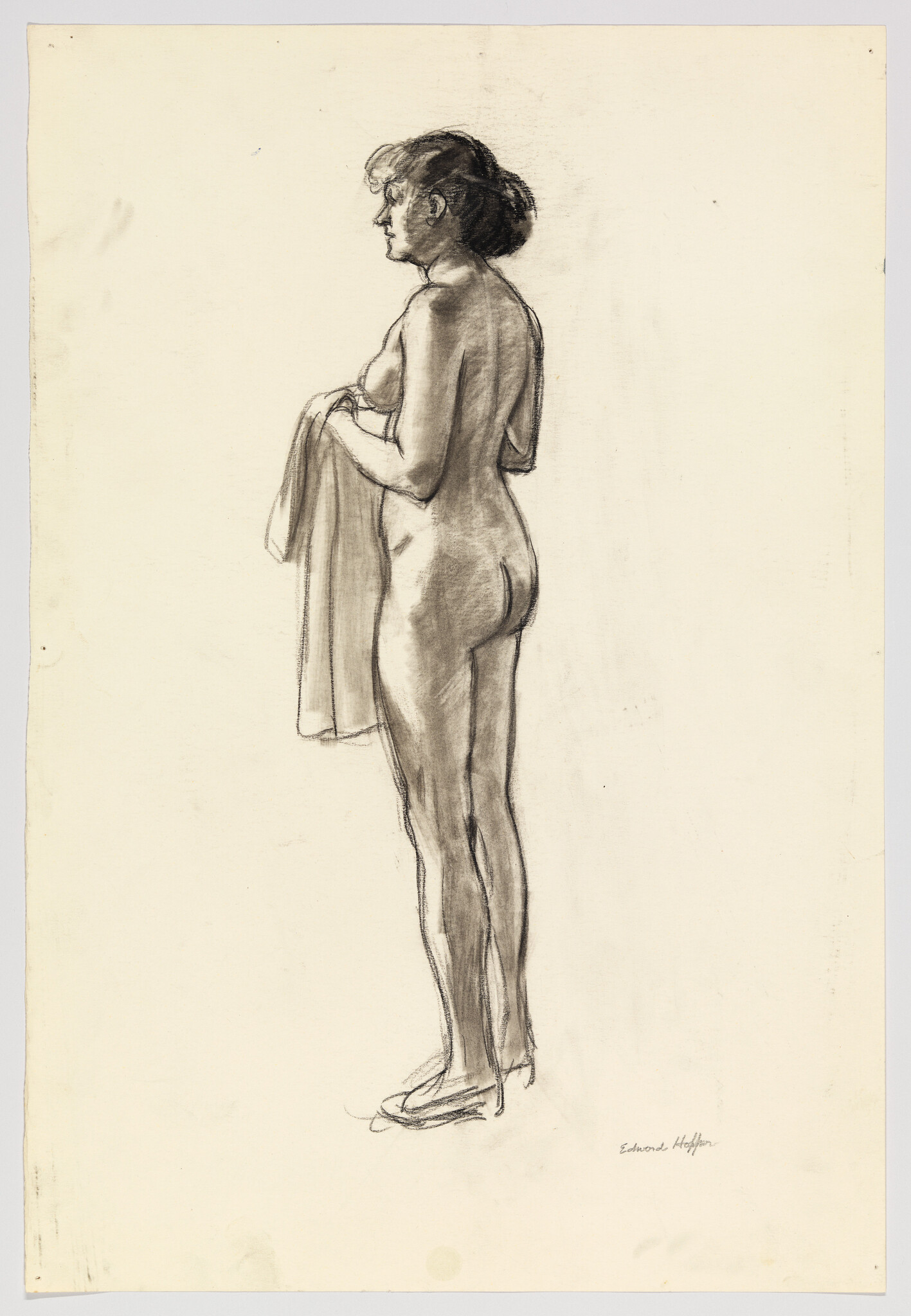 A standing nude woman holds a towel draped over her hands while looking left.