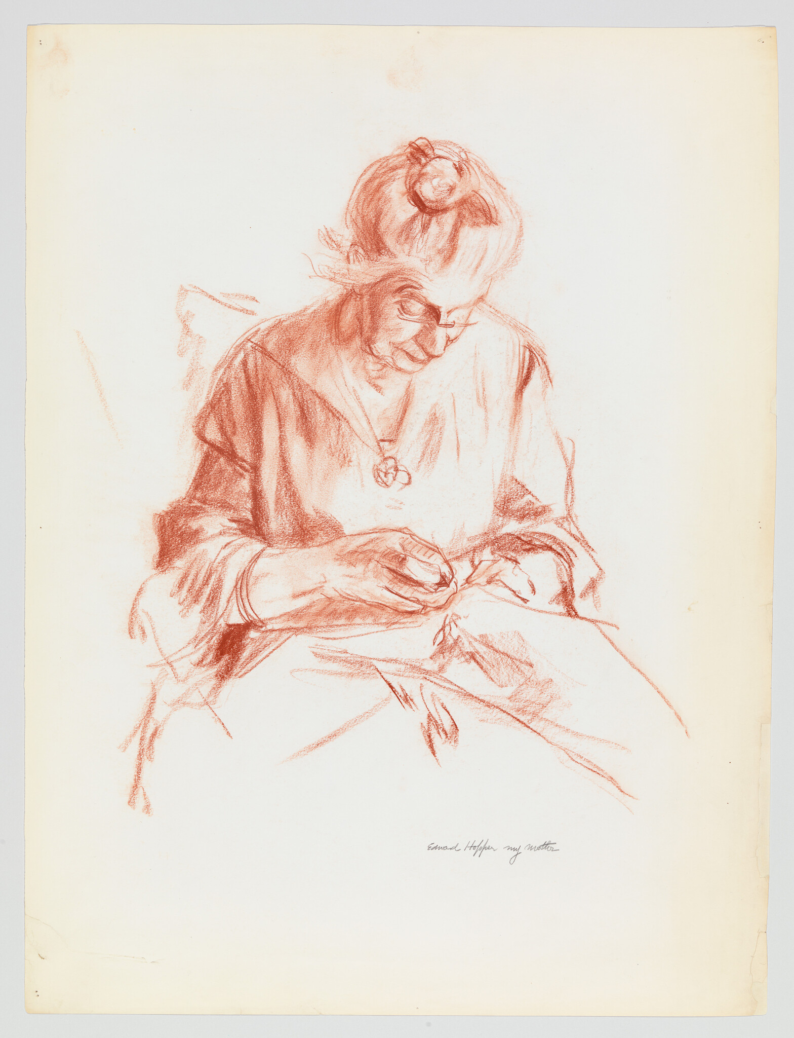 Older woman sitting and sewing fabric by hand, head bent over her work.