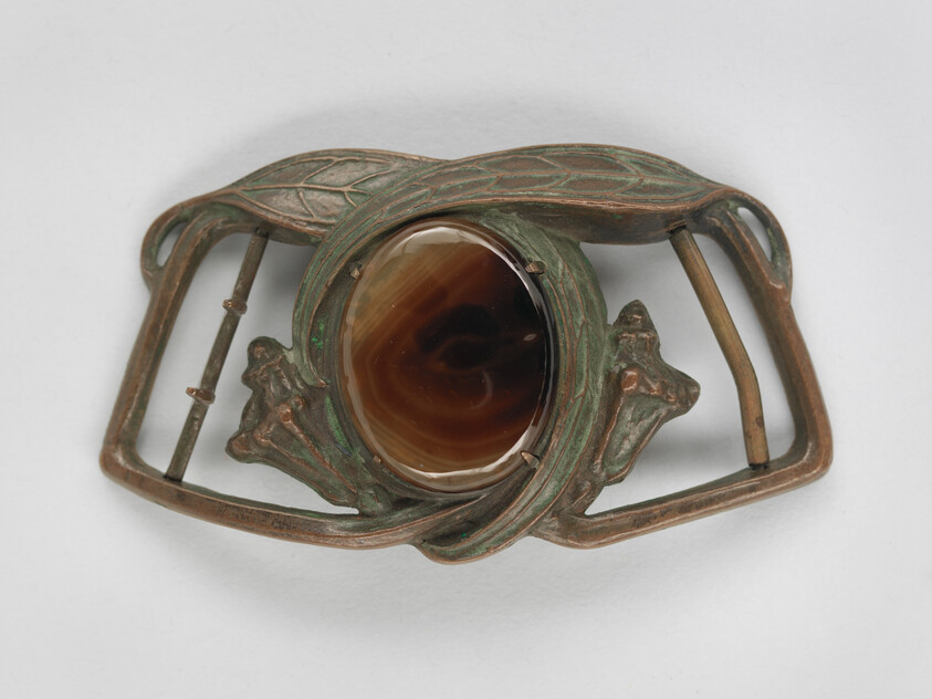 A decorative Art Nouveau belt buckle with a large polished brown agate set in patinated metal.