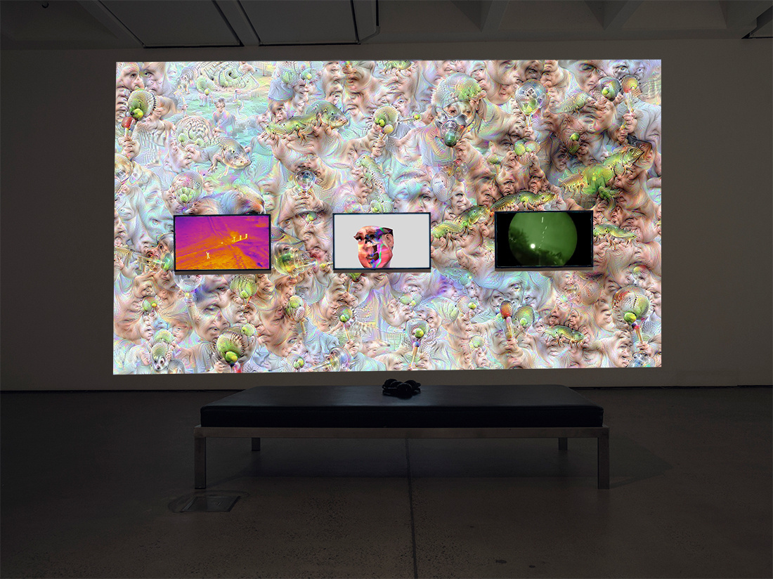 Three screens and one projection displaying generated psychadelic art, a 3D digital avatar, advertising and military footage.