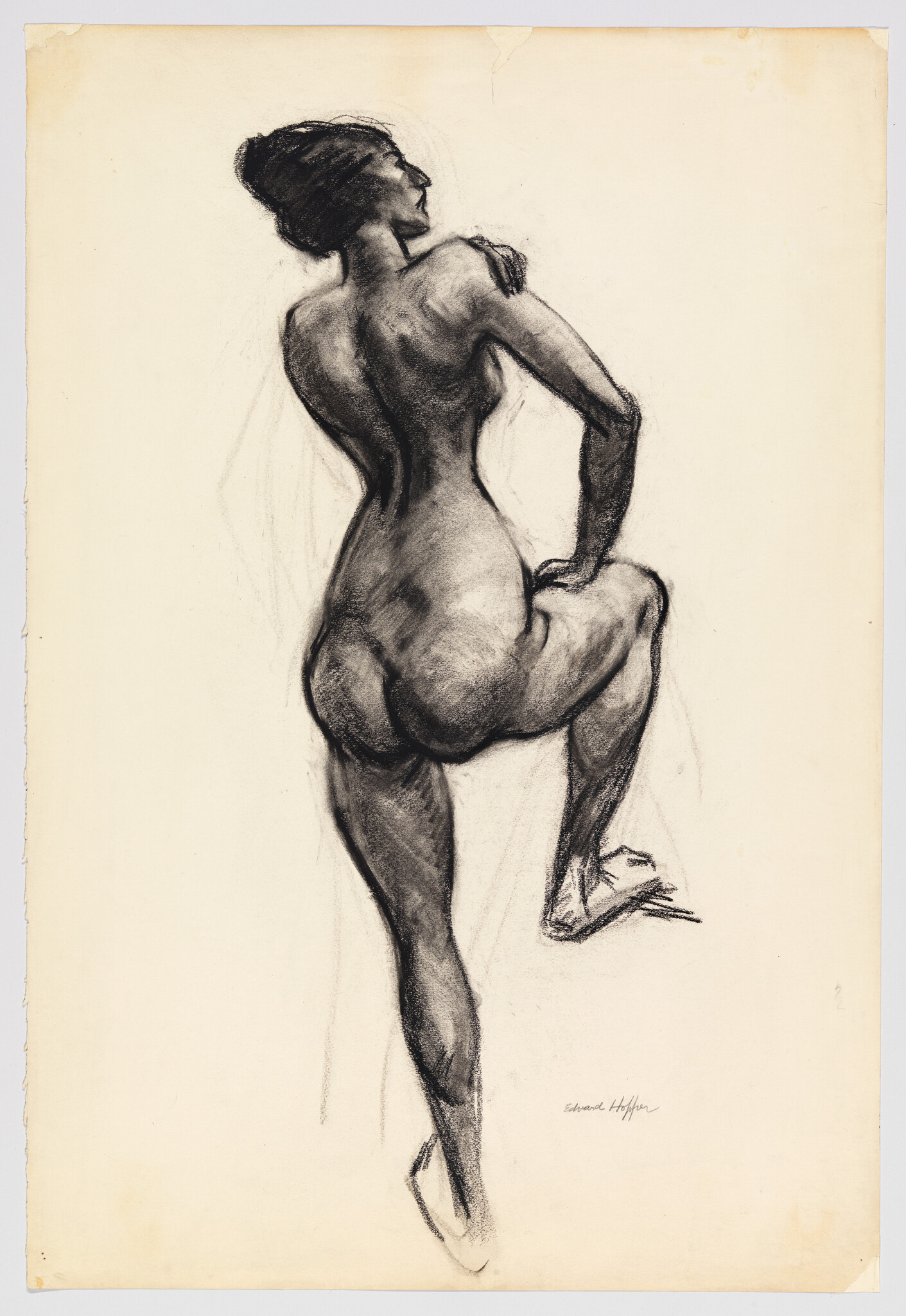 Nude woman seen from behind standing with one knee raised in a charcoal study.