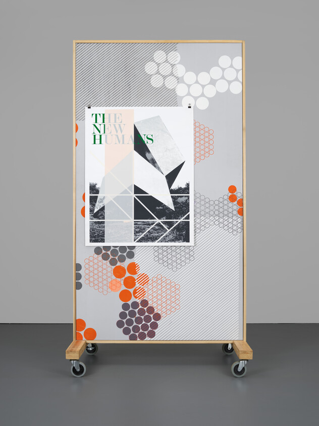 A modern, mobile partition screen with a geometric and abstract design, featuring a mix of patterns and textures in gray, white, black, and orange. The screen displays the text "THE NEW HUMANS" in bold, green letters and is set against a simple gray background. The partition is mounted on wheels for easy movement.