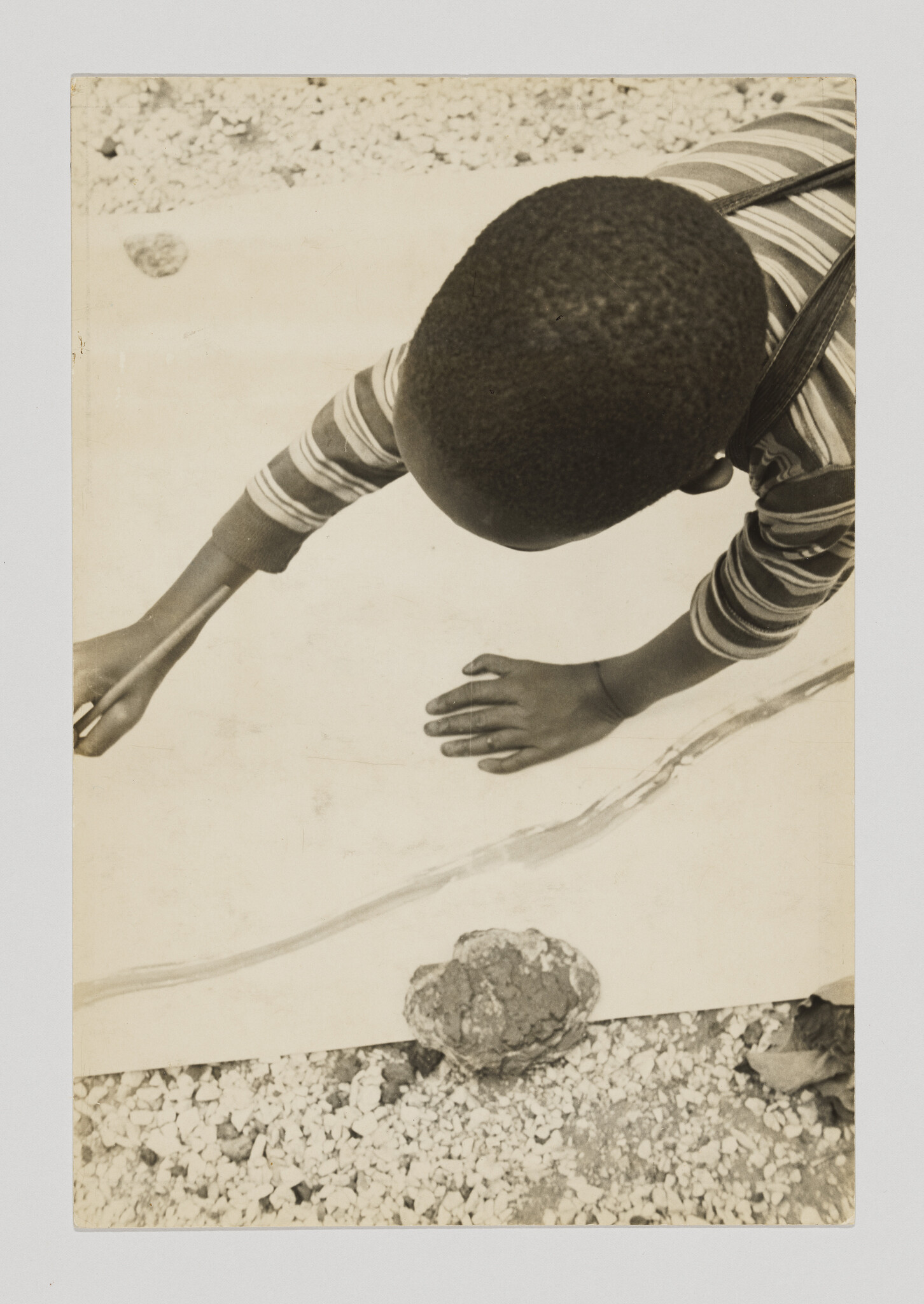 A child leans over a large sheet, drawing or tracing with hands on the paper.
