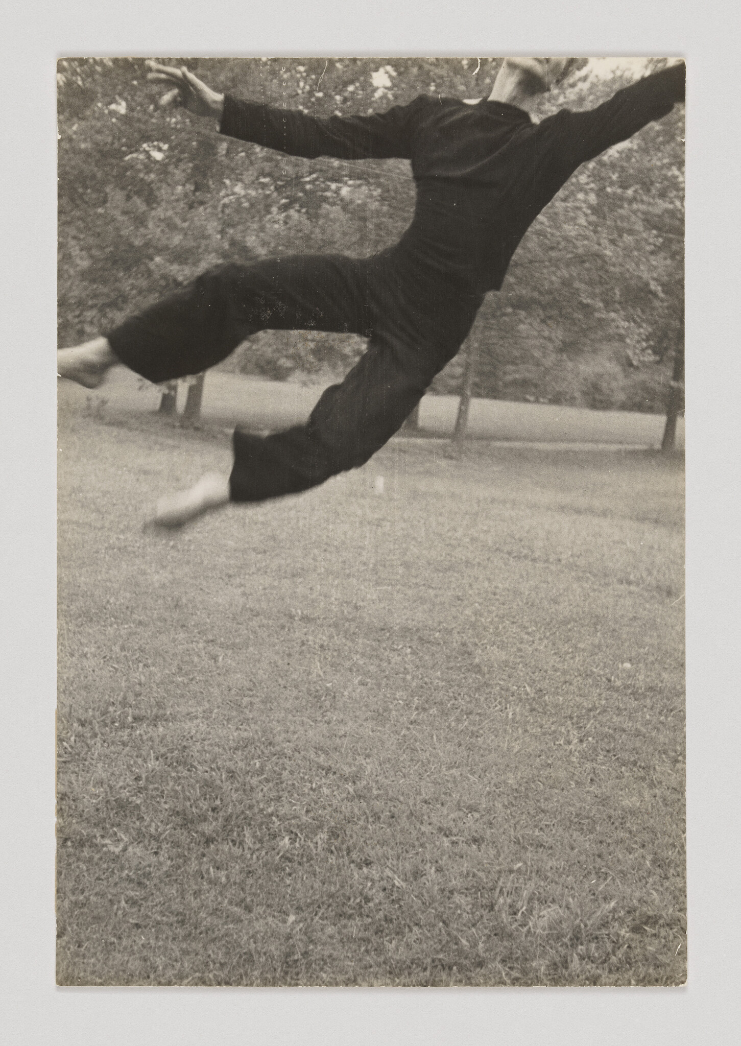 Person captured mid-leap against a blurred park background, giving the impression of floating. Vintage black and white photo.