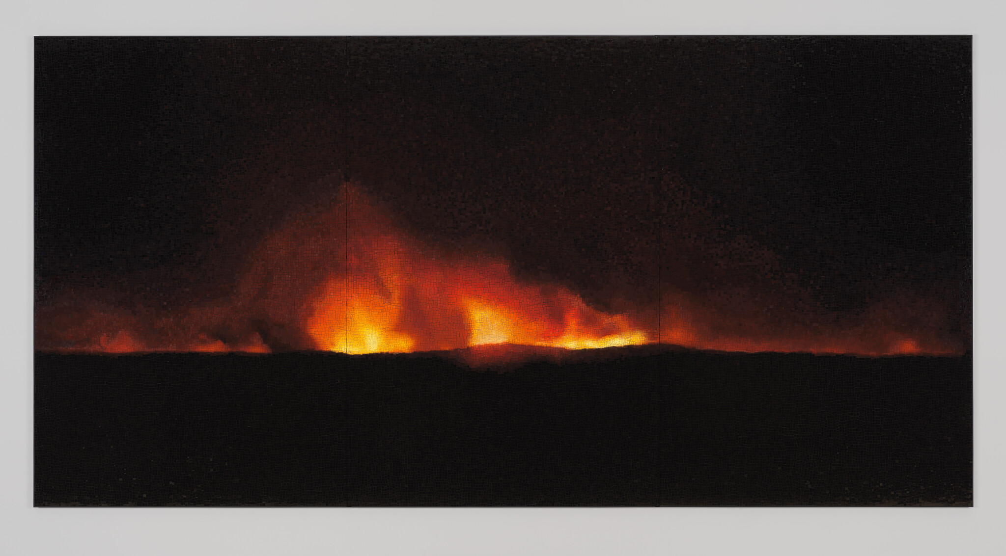 A wide line of bright orange flames and smoke rising along the dark horizon at night.