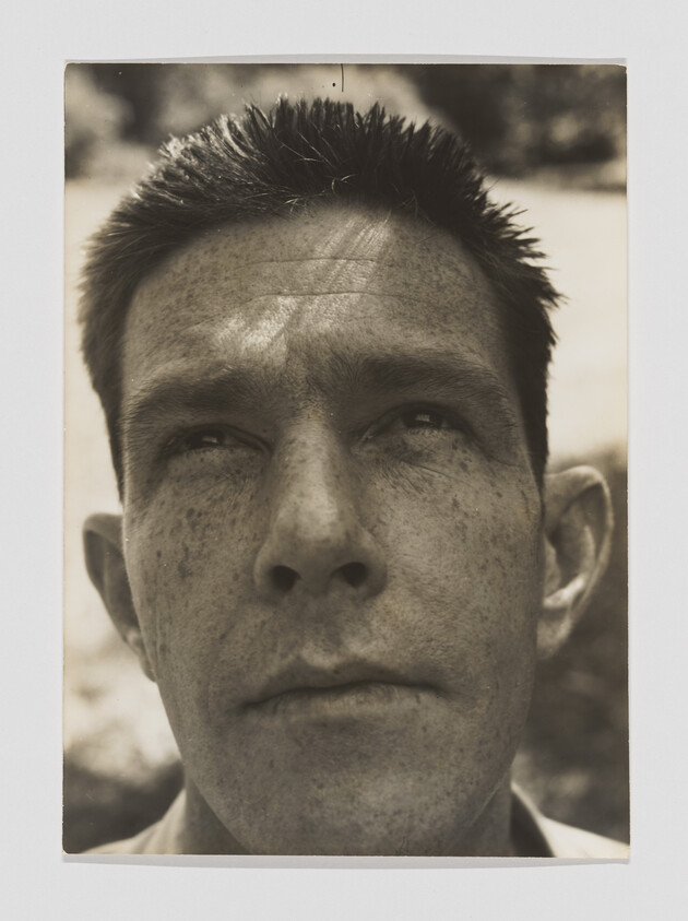 Close-up of a freckled man looking upward with a serious, contemplative expression.