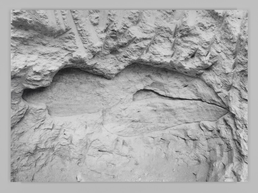 Rock wall with two long, hollowed-out horizontal cavities formed by erosion.