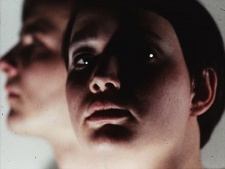 Close-up of a person’s face in deep shadow with a second blurred face behind.