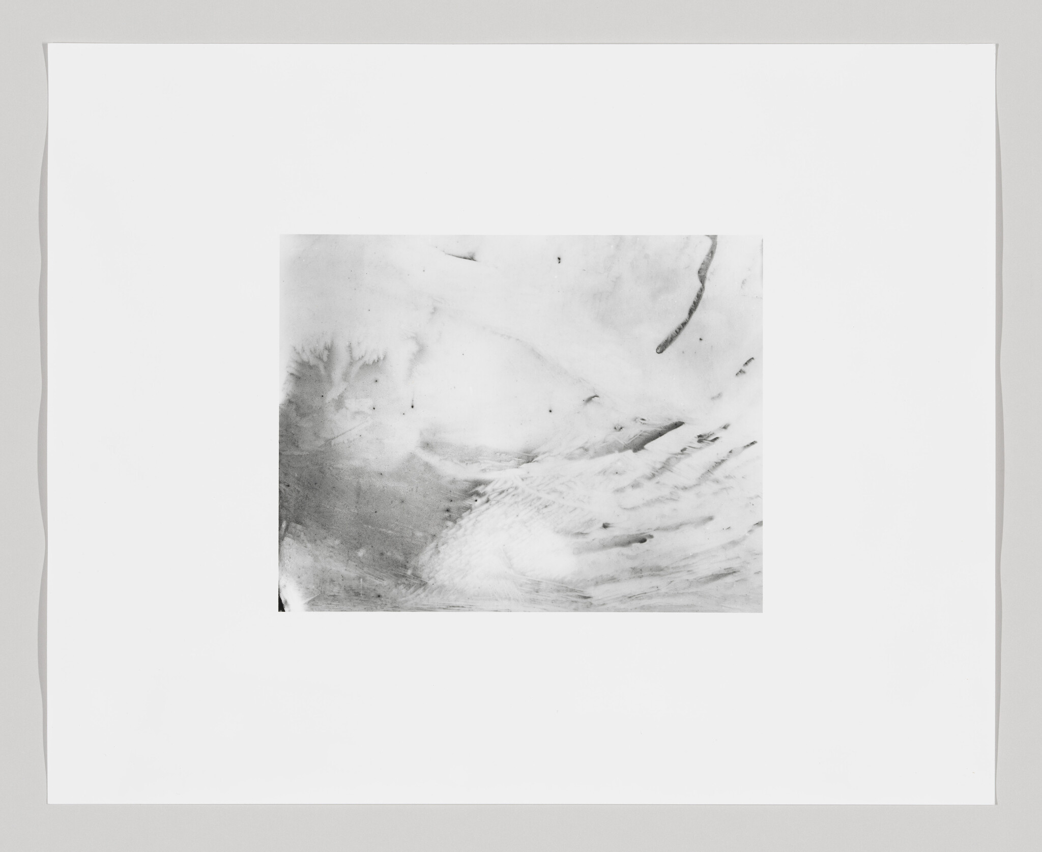 A monochromatic abstract artwork with various shades of gray, featuring fluid and dynamic marks that suggest movement, framed by a wide white border.