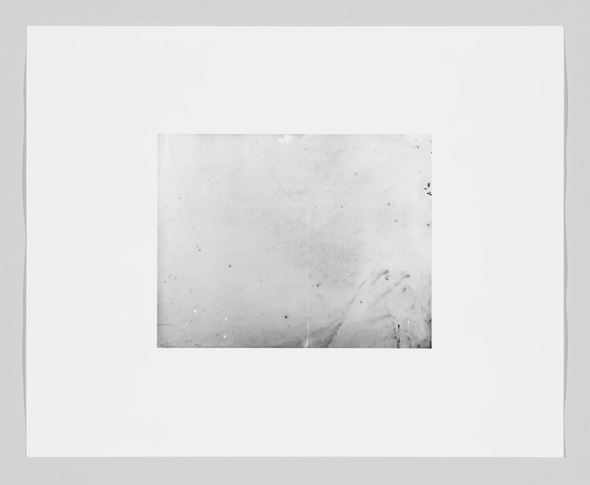A blank polaroid photo with a white border and a central image area that appears overexposed or undeveloped, resulting in a mostly white space with some minor blemishes and specks.