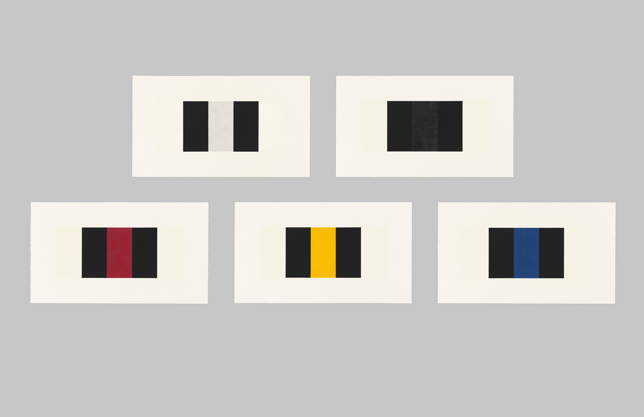 Five framed abstract geometric artworks on a gray wall, each featuring a different arrangement of colored rectangles on a white background.