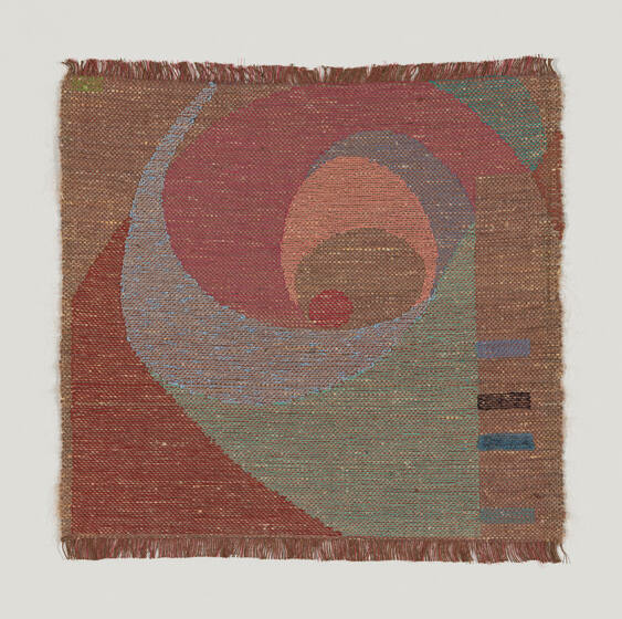 A woven tapestry featuring an abstract design with a prominent spiral pattern in shades of red, blue, and green, with a textured, fringe border.