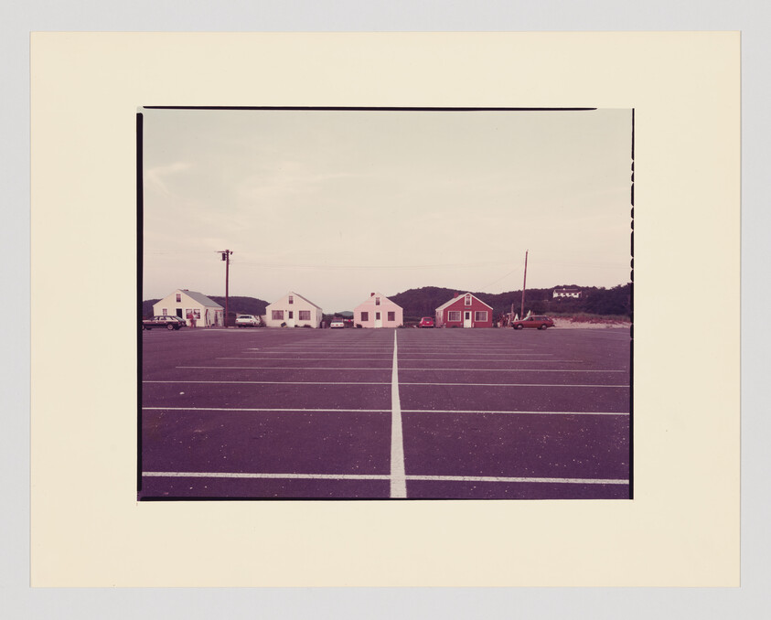 Empty parking lot with painted center line leading to a row of small coastal houses.