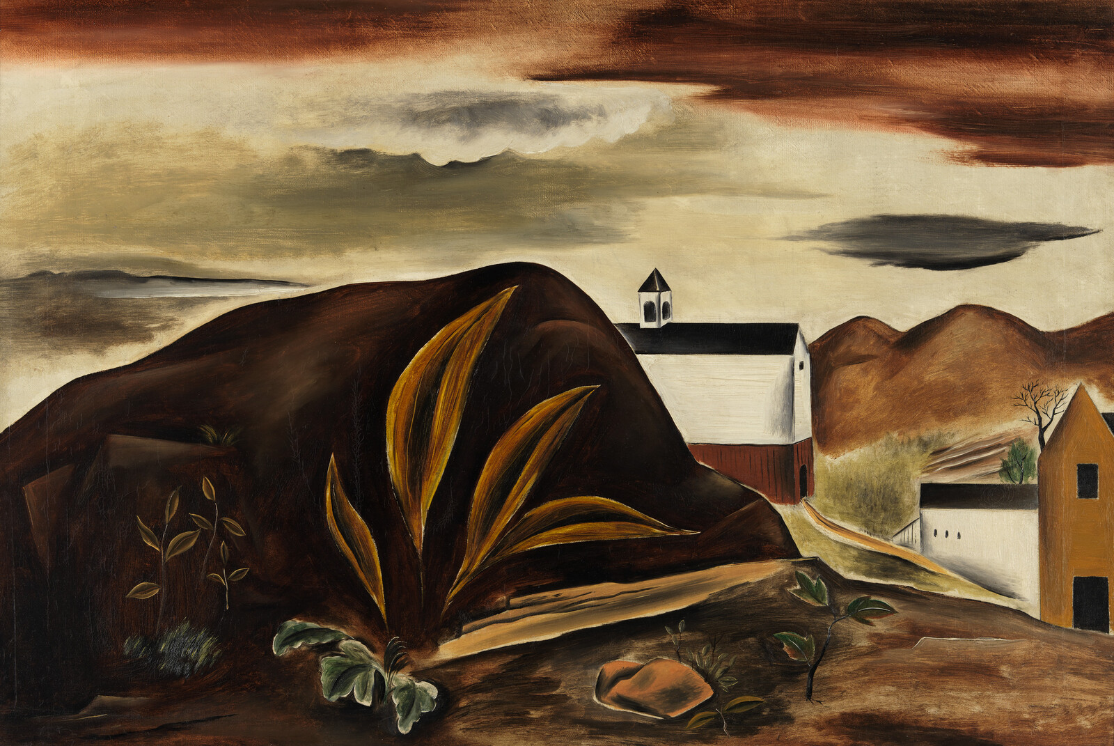 Large dark hill with golden plants sits before a white church under a cloudy sky.