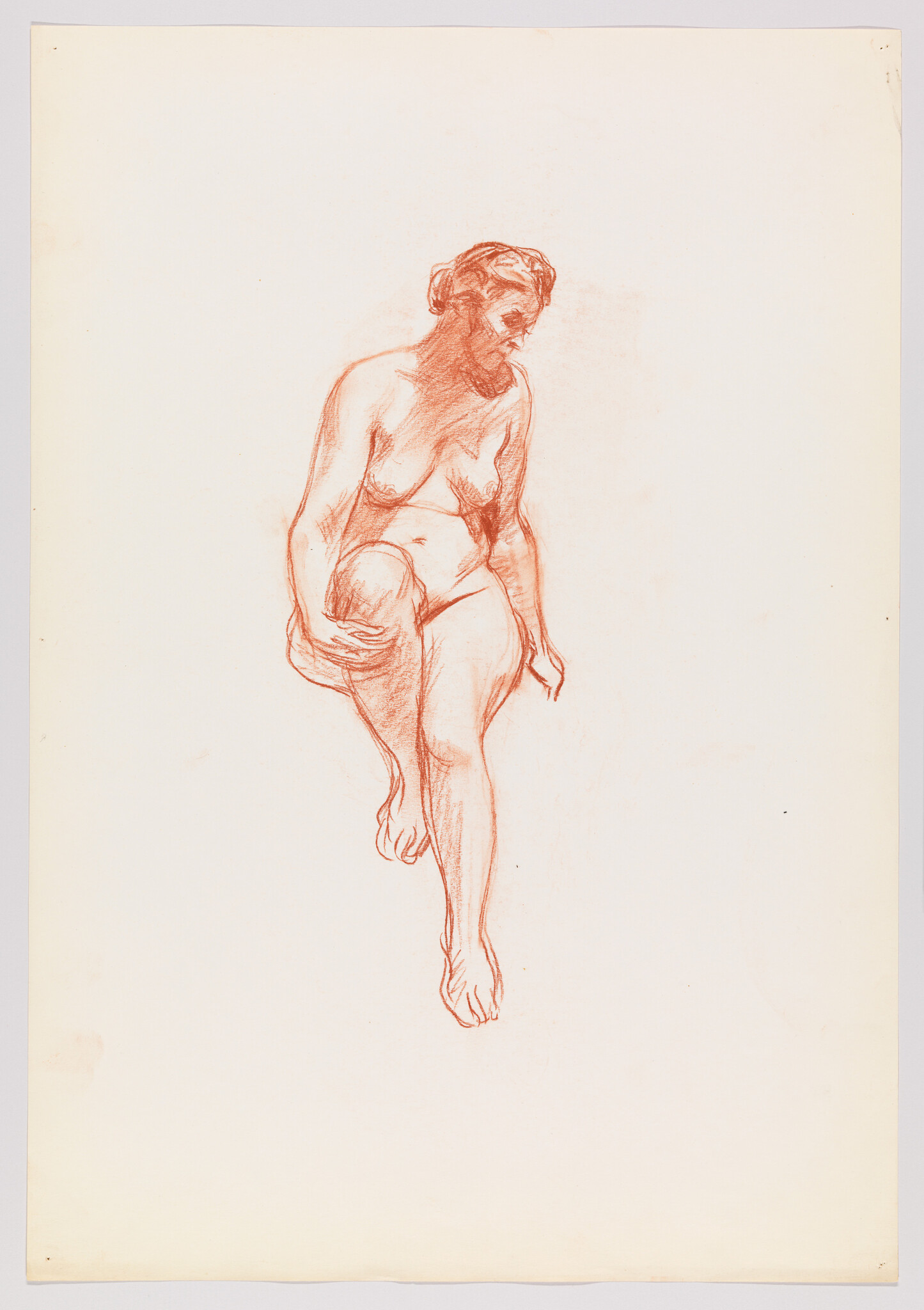 A red chalk drawing of a nude woman lifting one knee while seated and looking down.