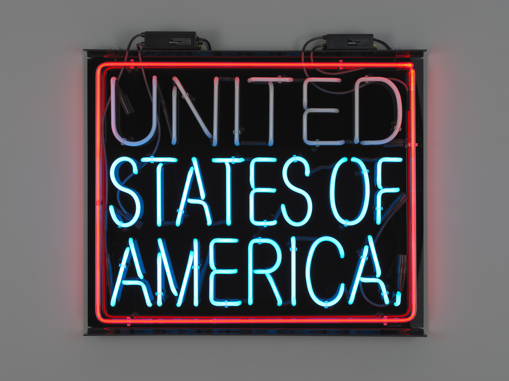 A neon sign on a wall glowing "United States of America" in red and blue.