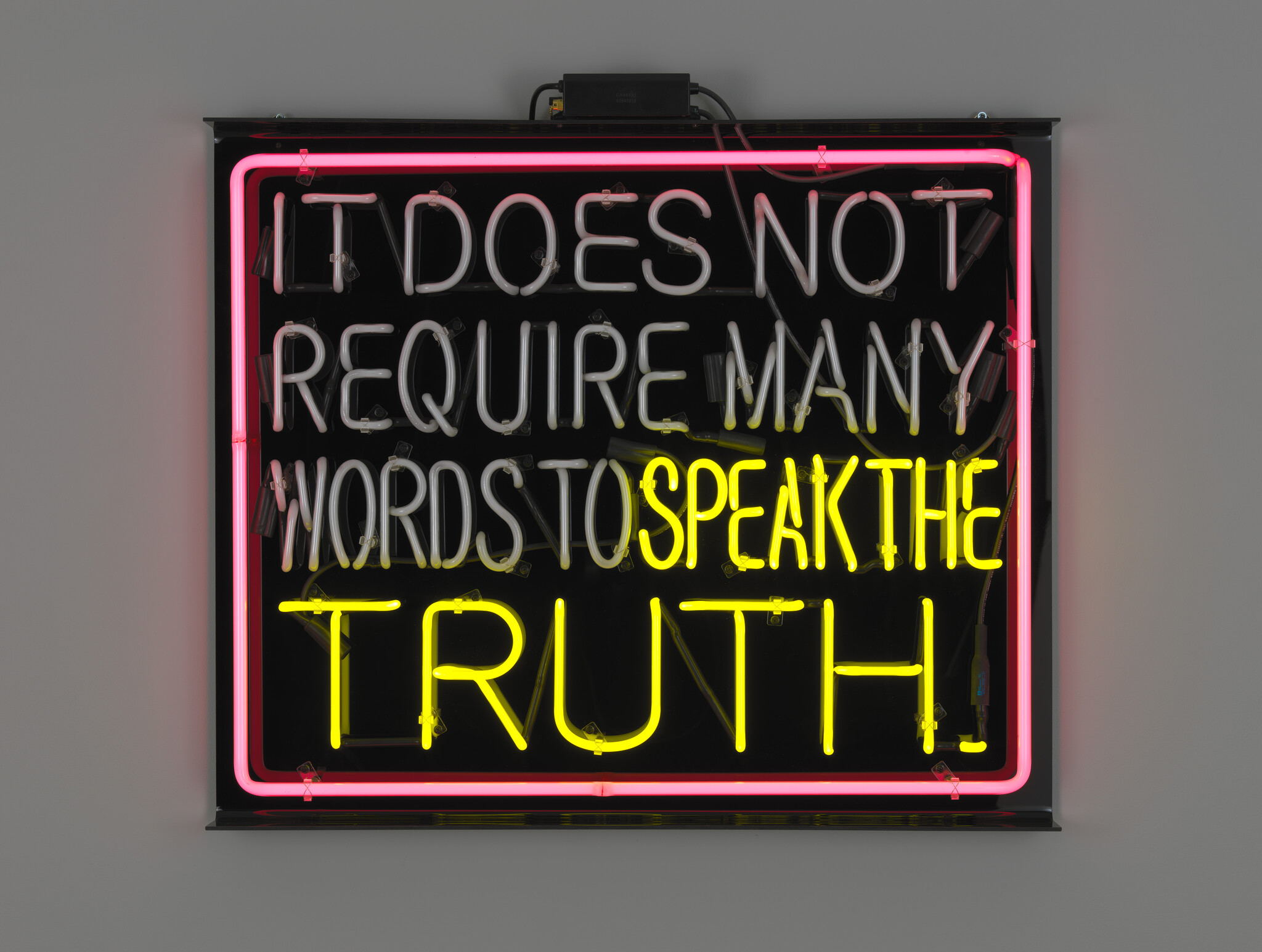 A neon sign with pink, white, and yellow tubing reading "It does not require many words to speak the truth."