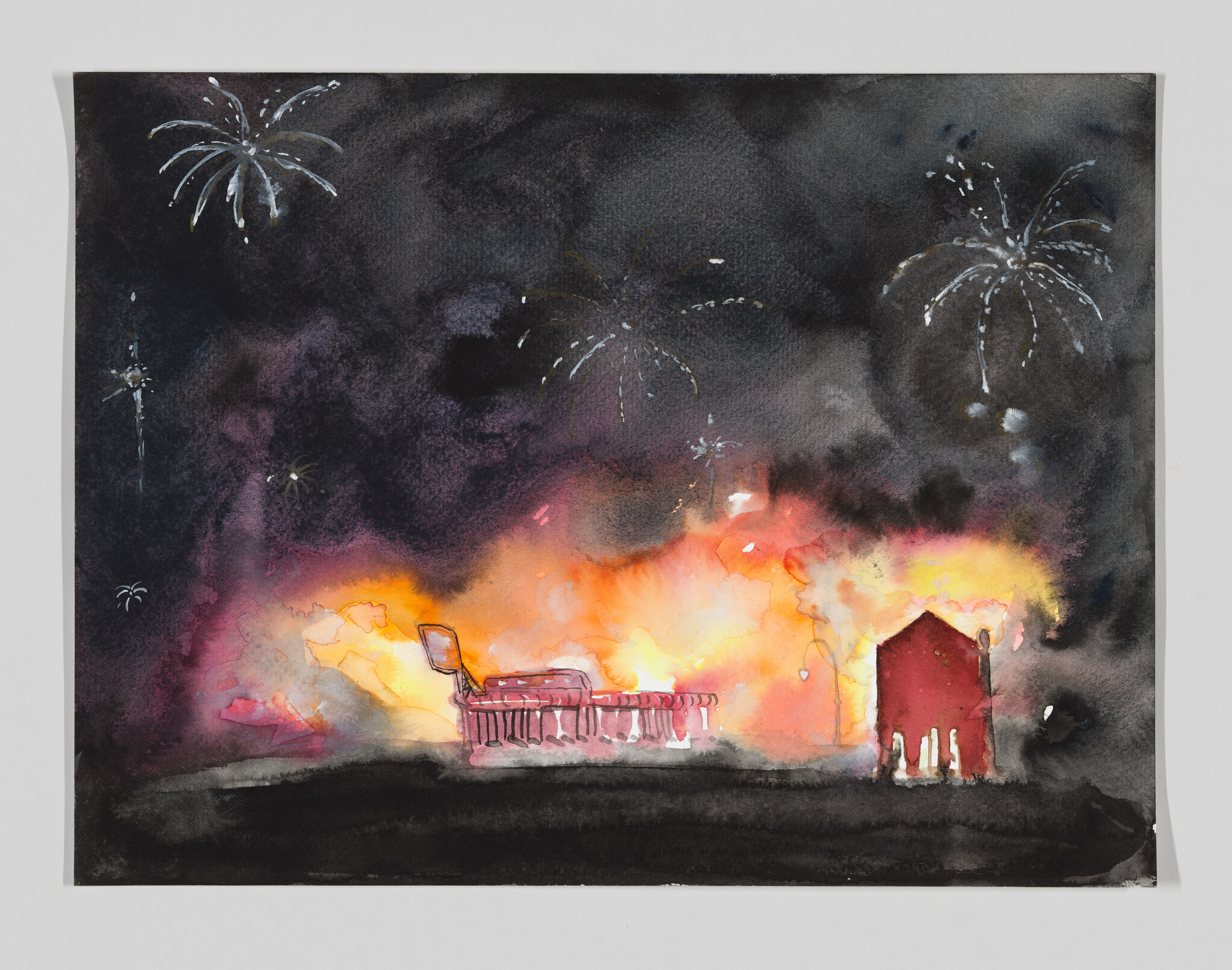 Nighttime fire engulfs a small building and area while distant fireworks burst overhead.