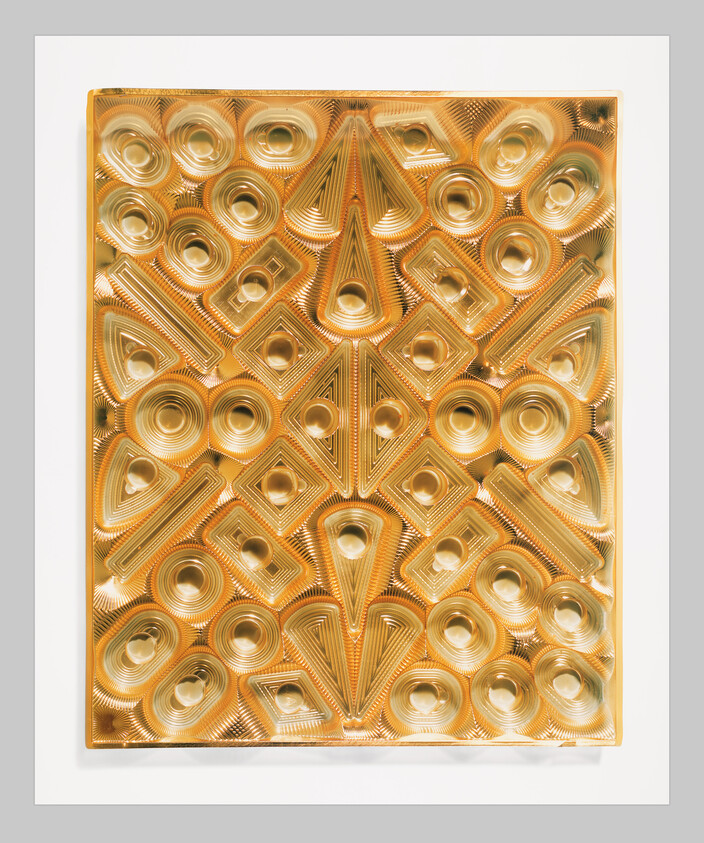 A gold embossed geometric panel with concentric circles and triangular shapes on a white background.