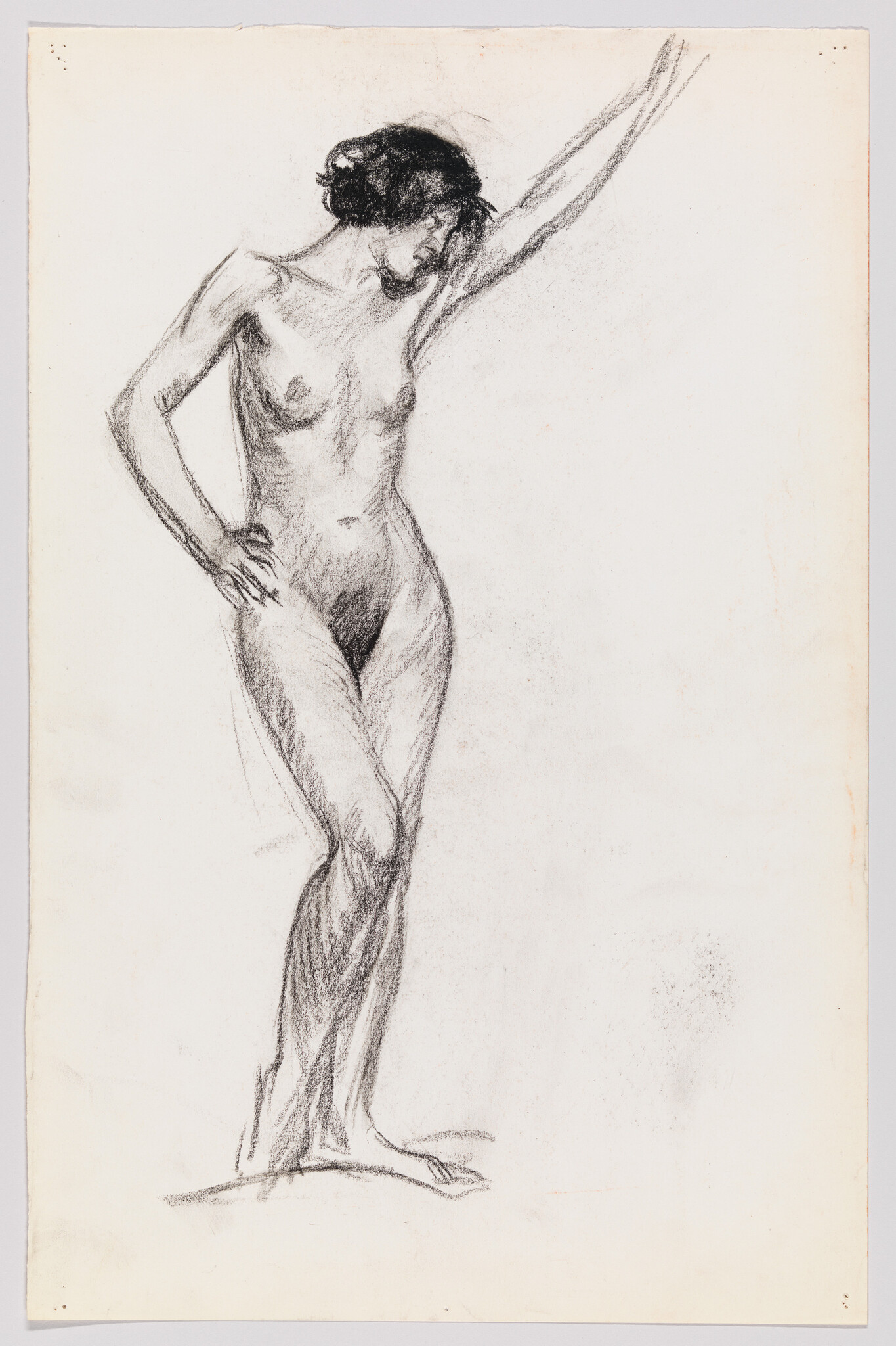 A standing nude woman drawn in charcoal with one arm raised and a hand on her hip.