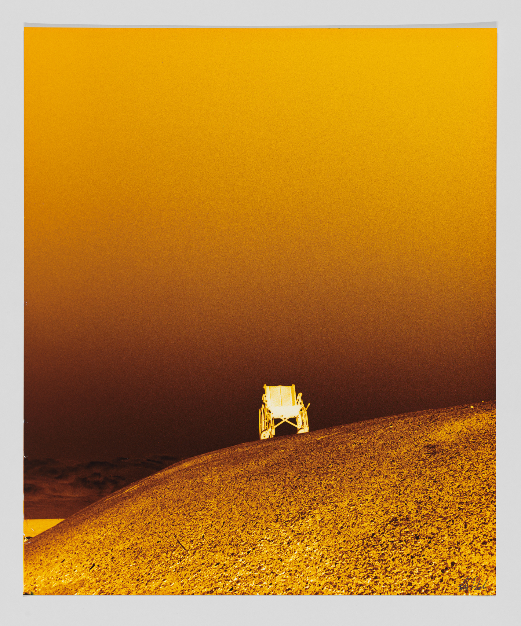A photo of a wheelchair on a hill. The colors have been inverted and the whole photo is in shades of orange.