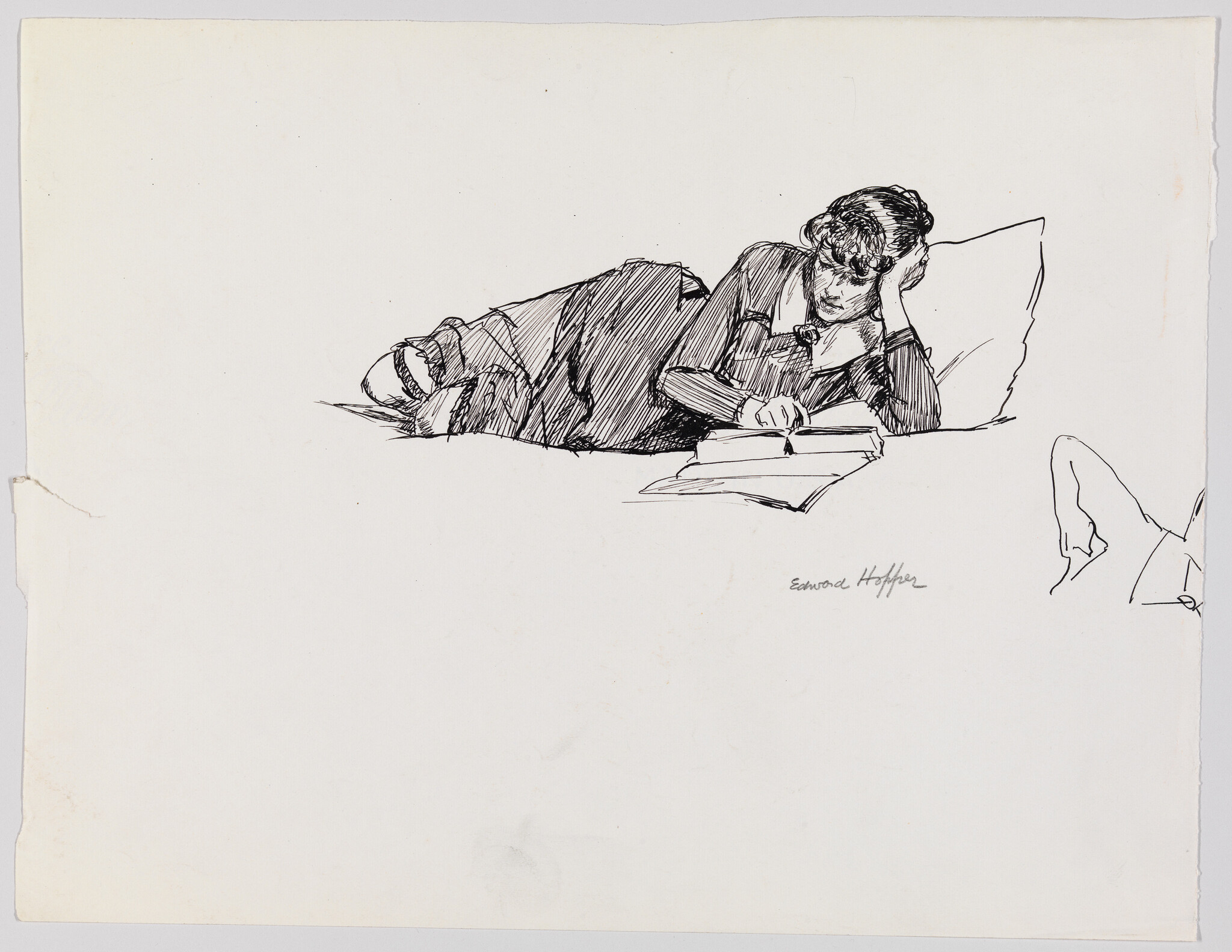 A person lying on their stomach propped on a pillow, reading a book intently.