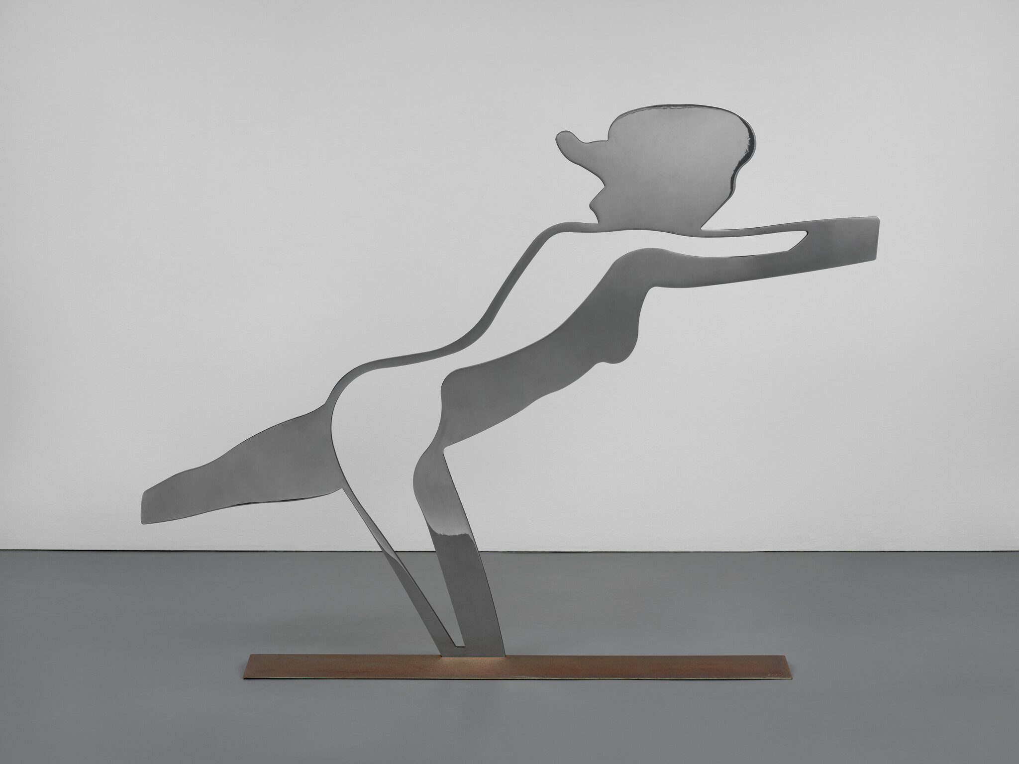 A metal silhouette sculpture of a person leaning forward with arms outstretched, mounted on a rectangular base.