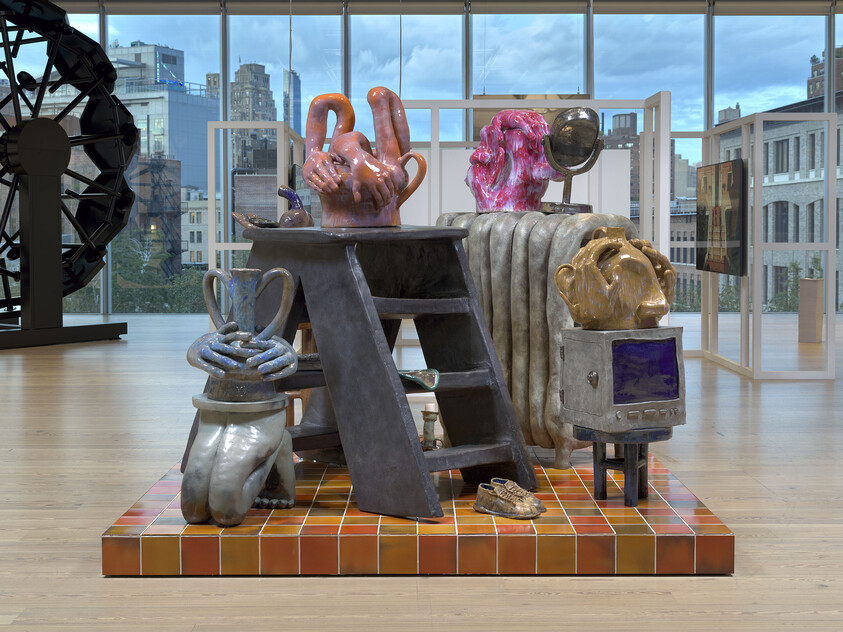 Colorful sculpture with abstract animal and human shapes, a ladder, a radiator, and a box with a screen.