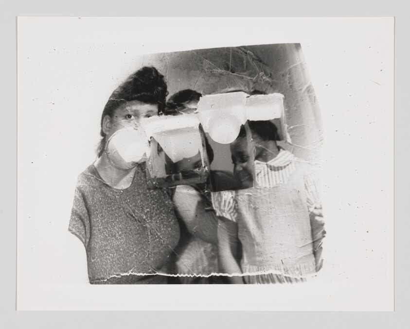 Three children stand close together, but their faces are partly covered or distorted by a damaged or altered photo.