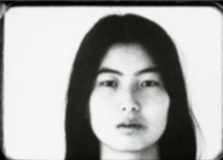 Close-up black-and-white portrait of a young woman with long dark hair and neutral expression.