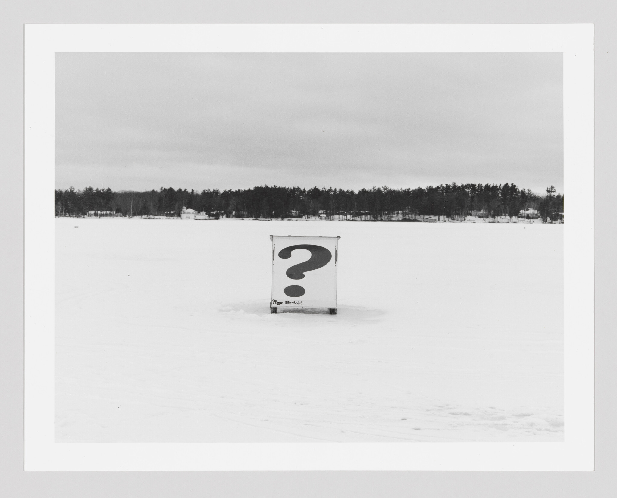 A small box with a large question mark sits alone on a snowy frozen lake.