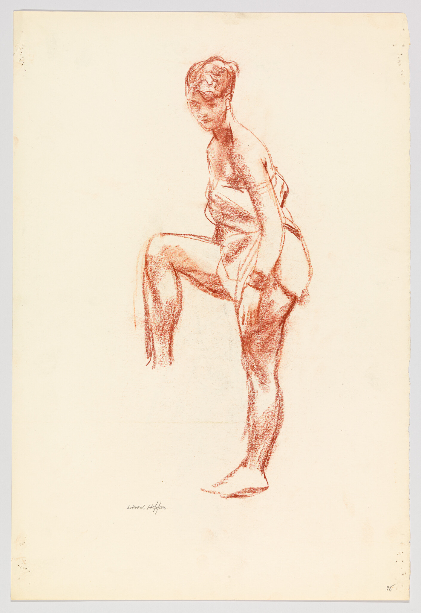 Woman wrapped in cloth lifts one knee while standing on the other leg.