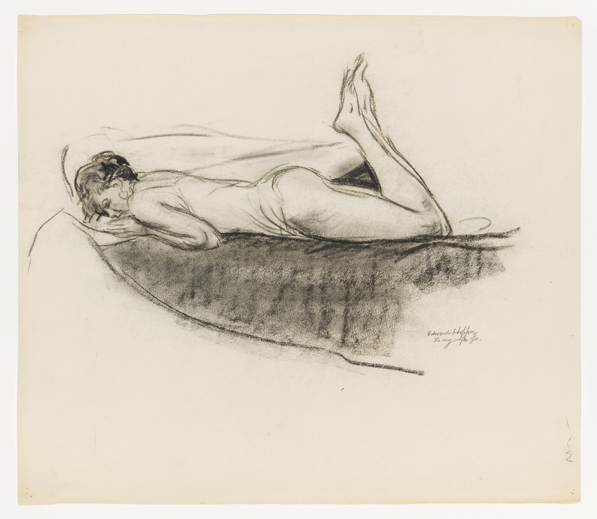 A person lies face down on a bed with knees bent and feet raised.