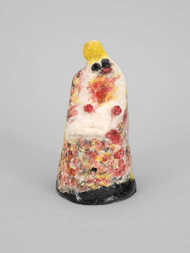 A textured, abstract painted sculpture with a yellow top and red splotches on a grey background.