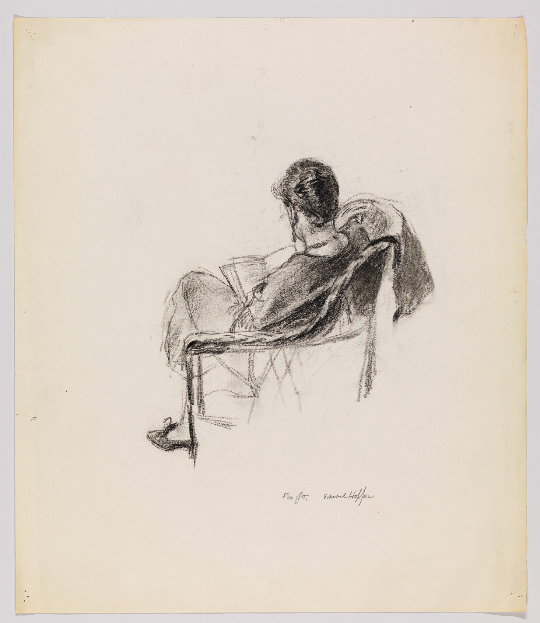 A woman sits in a chair leaning back and reading a book.