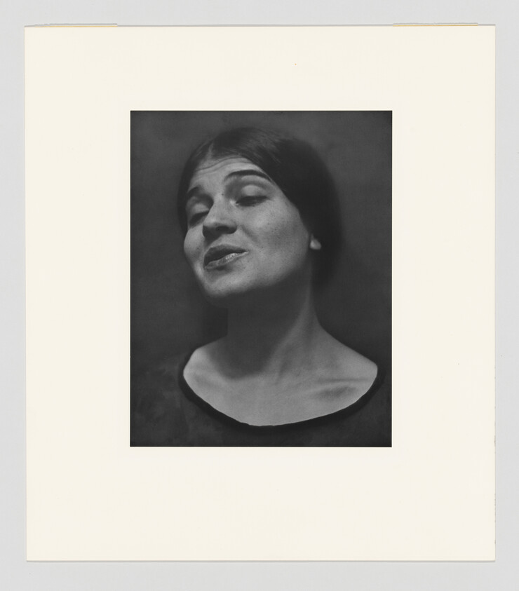 Young woman tilts her head back slightly with eyes half closed and a subtle smile.