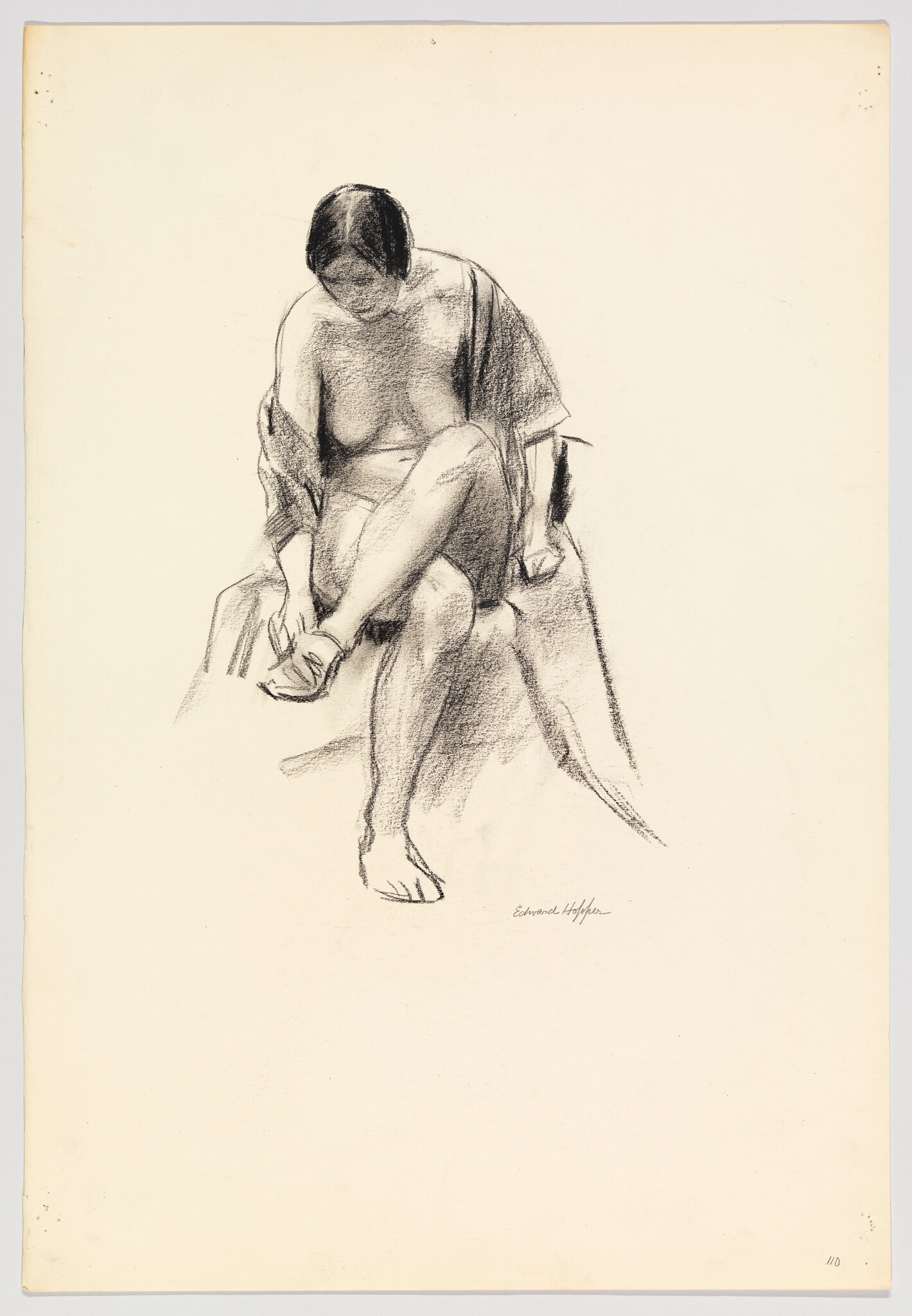 Seated woman leaning forward, lifting one leg to adjust her sandal while looking down.