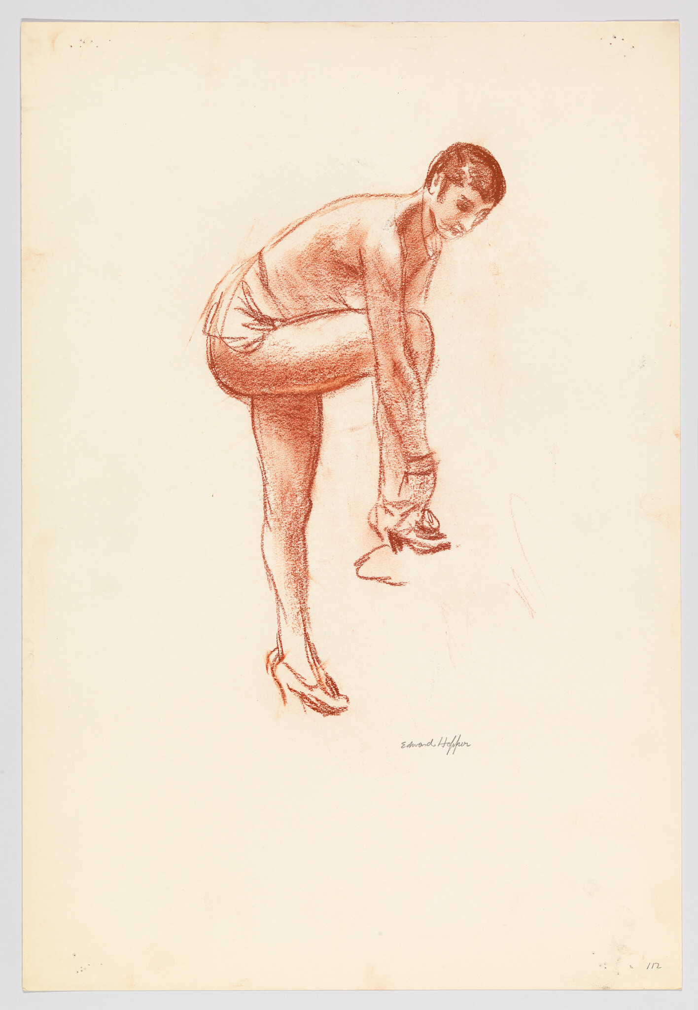 A person bends forward, lifting one leg and fastening a shoe while looking back.